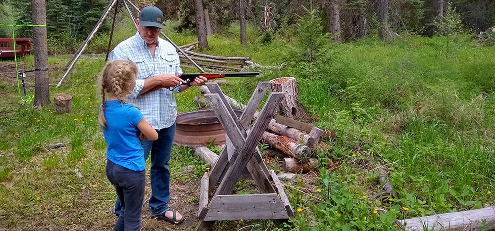image: man teaching young girl to shoot gun