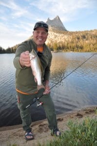 Man fishing trout in lake at Yosemite National Park with El Capitan in background