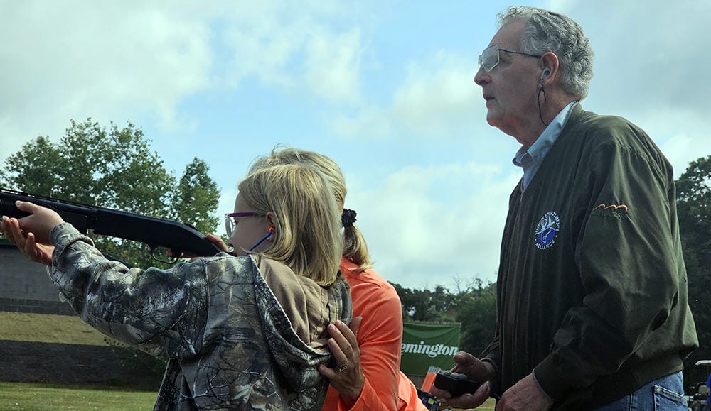 image: adult teaching youth to shoot sporting clays.