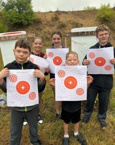 image: kids hold rifle targets
