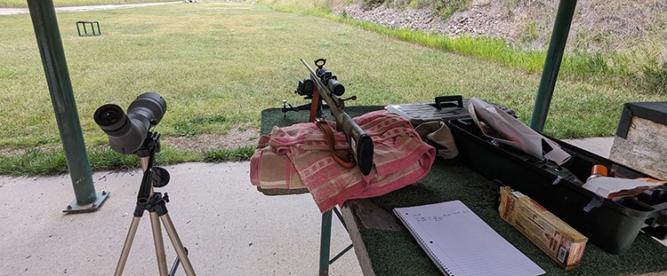 image: rifle and gear at shooting range.