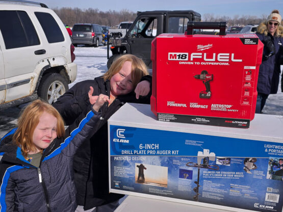 Take Kids Ice Fishing participants stand next to raffle prizes.