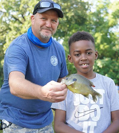 Image: Ironworker assisting youth with caught fish