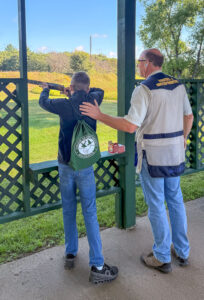 Photo of Roofers volunteer instructing youth shooter. 