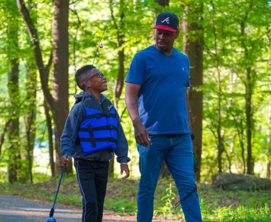 Father and son walking with fishing pole.