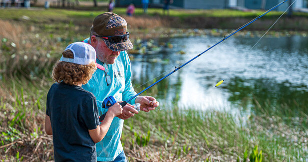Man and kid bait fishing hook at lake. 