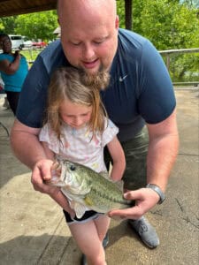 A father holds a fish with his daughter at the Louisville Take Kids Fishing Day.
