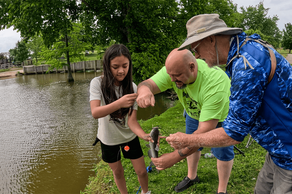 KY TKF Union volunteers help a youth angler reel in a fish at the Lexington Take Kids Fishing Day.