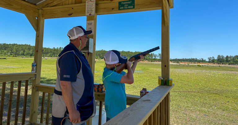 Youth shooter with volunteer at sporting clays range.