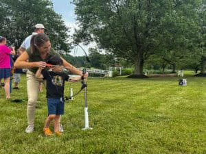 A kid shoots archery with adult